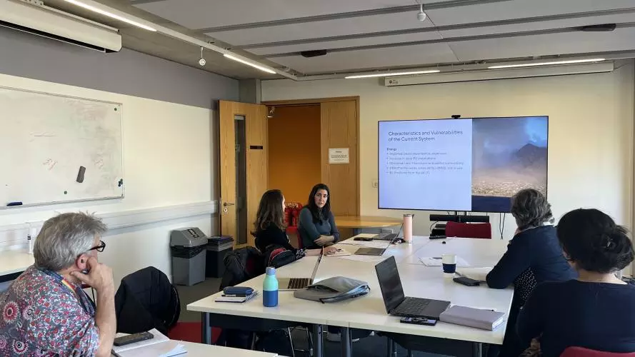 Researchers seated around a table listening as Professor Yael Parag gives a presentation.
