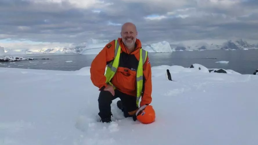 Professor Mike Kendall kneels in the snow during fieldwork in Antarctica.